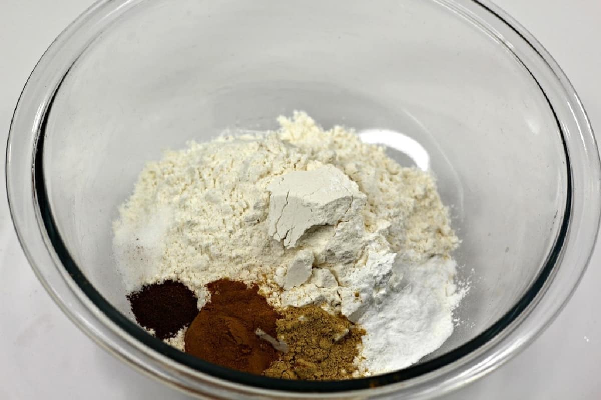 Flour, baking soda, baking powder, and spices in a glass bowl.