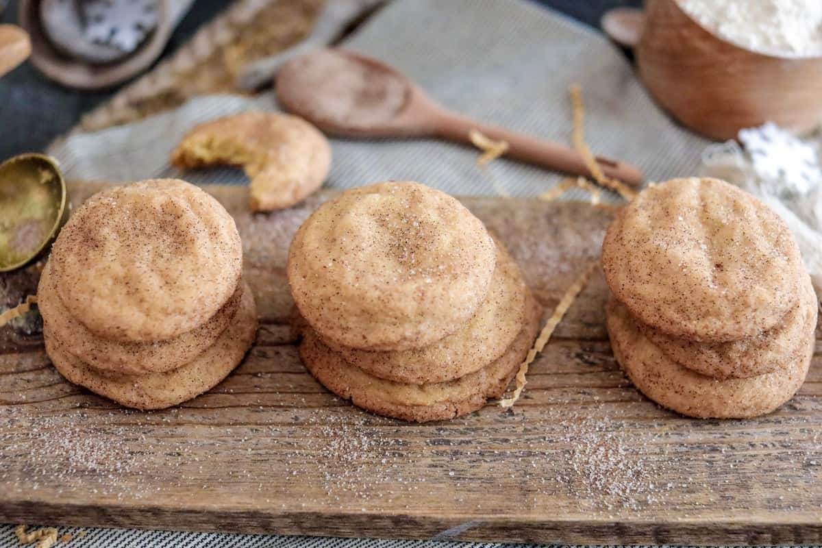 Cookies with sugar and cinnamon on wood board with flour and spoon in background.