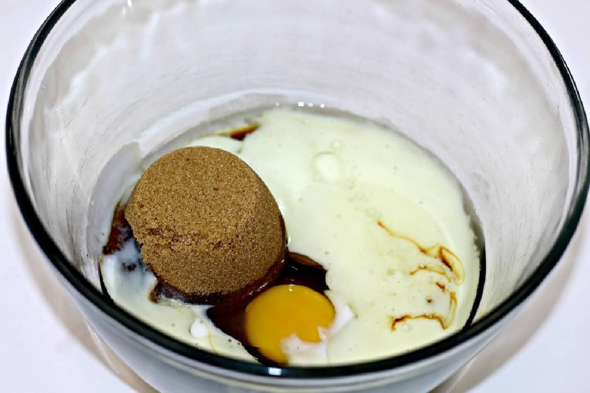 Egg, milk, brown sugar in a glass bowl.