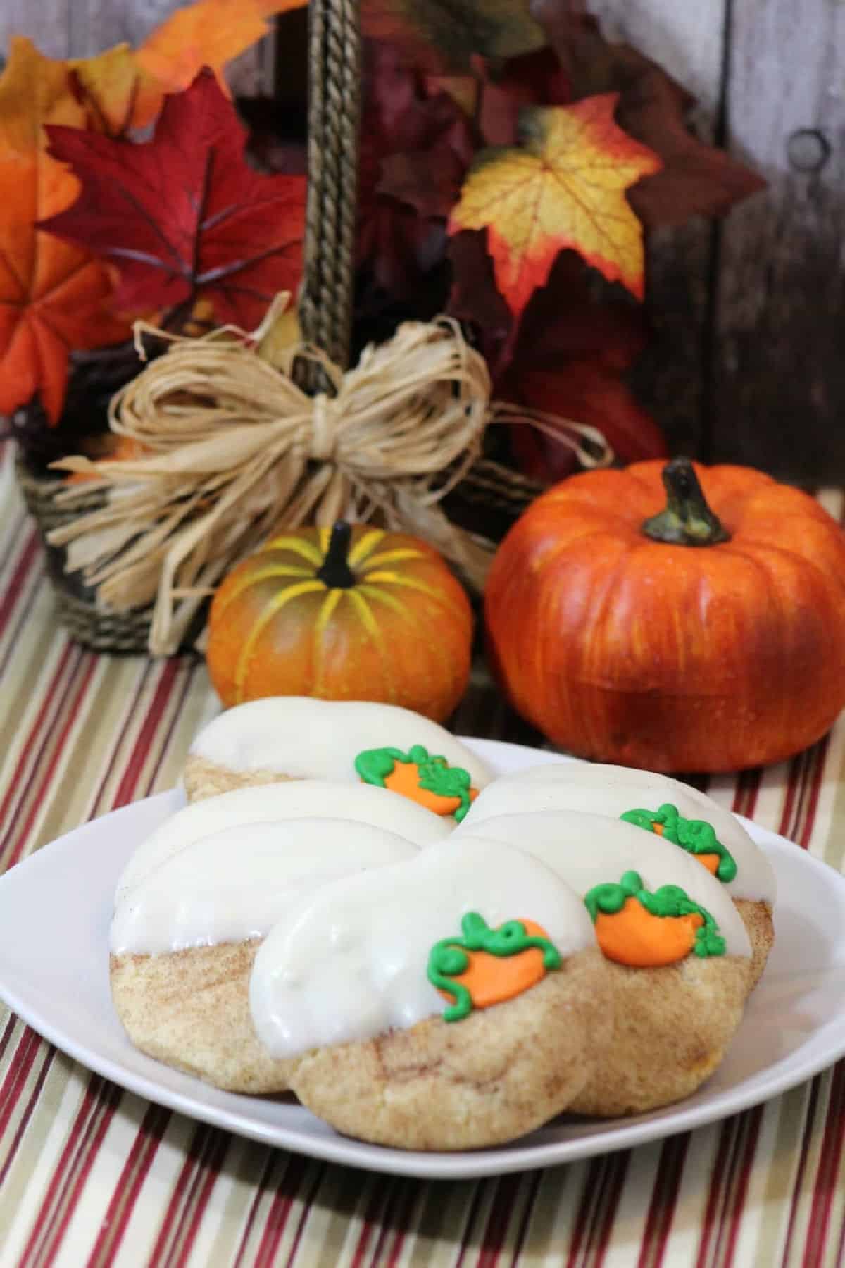 Pumpkin snickerdoodle cookies with pumpkins in background on a striped tablecloth.
