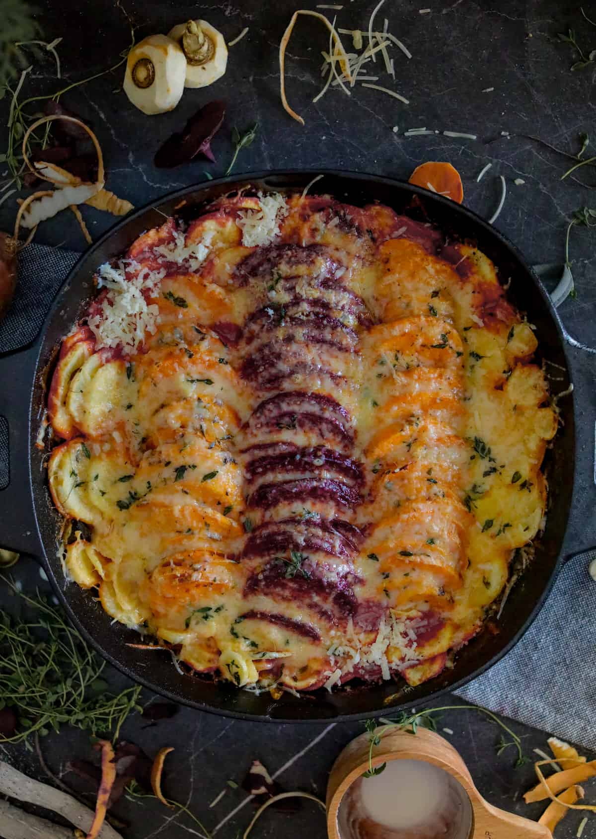 Root vegetables with cheese sauce in a cast iron casserole dish.