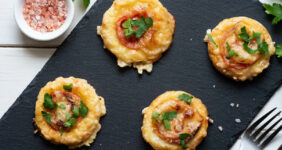Tomato tarts on a black board with salt, pepper, parsley, and tomato for Pinterest.