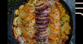 Root vegetables in a black pan with cheese on top, image for Pinterest.