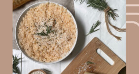 Risotto with rosemary, bread, cheese, and rice on a white table.