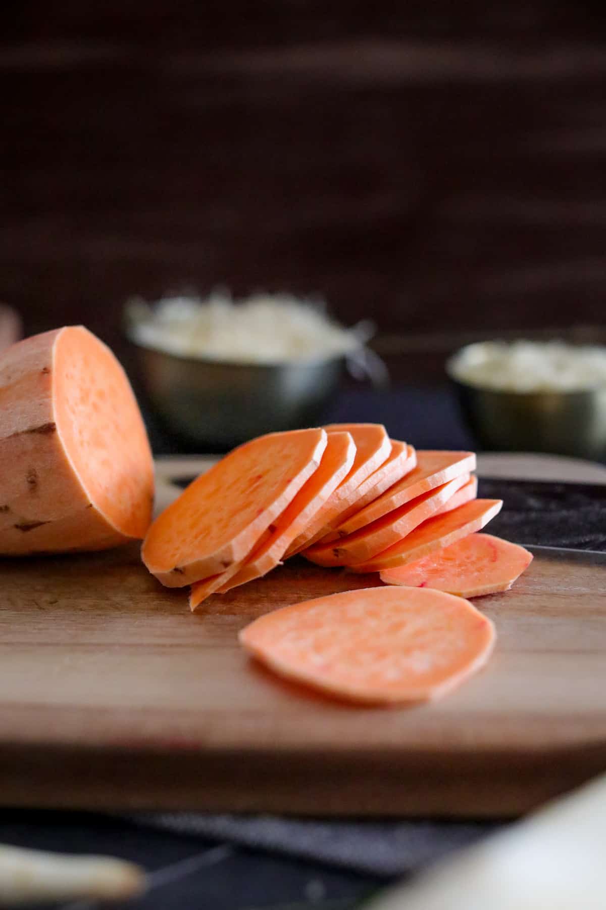 Sliced sweet potato on wood cutting board.
