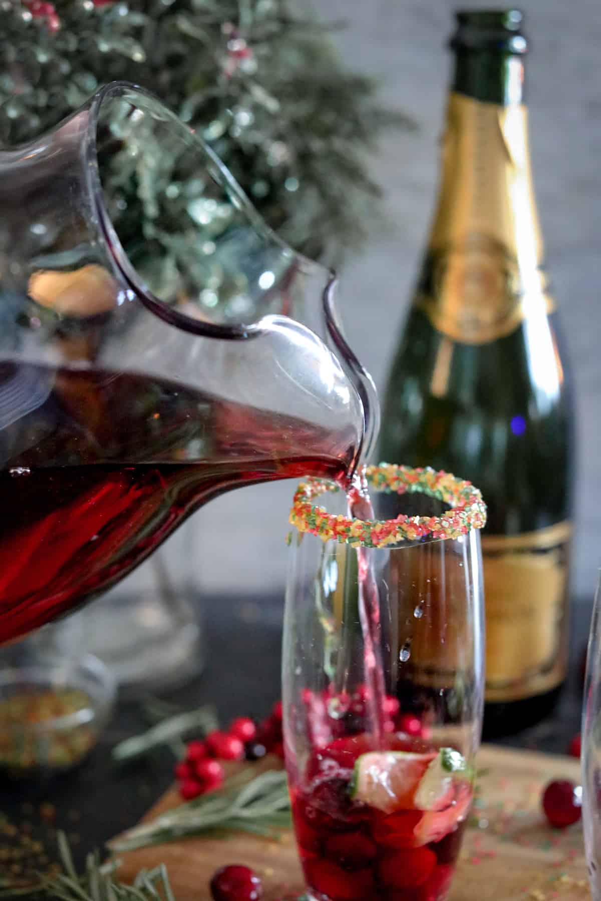 Pouring cranberry juice cocktail into fluted glass.