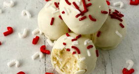 Cookie dough bites with red and white sprinkles on a wood table.