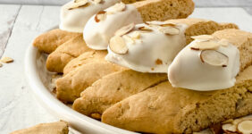 Biscotti dipped in white chocolate on a white table for Pinterest.