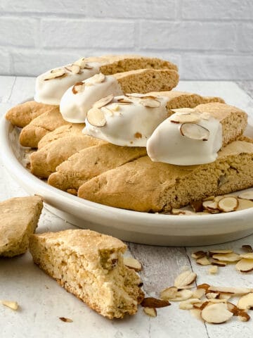 Biscotti dipped in white chocolate on a white table.