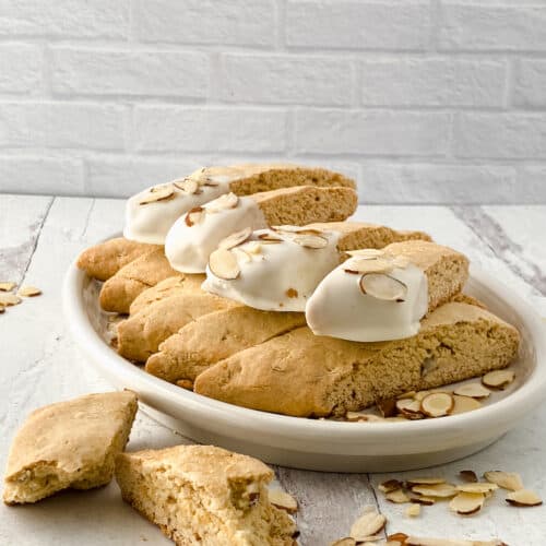Biscotti dipped in white chocolate on a white table.