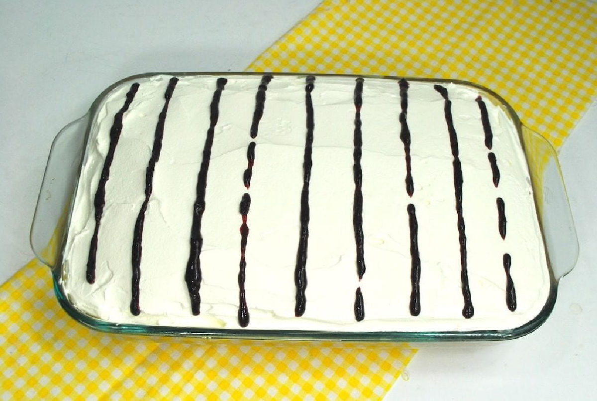 Rectangular cake frosted with blueberry drizzles.