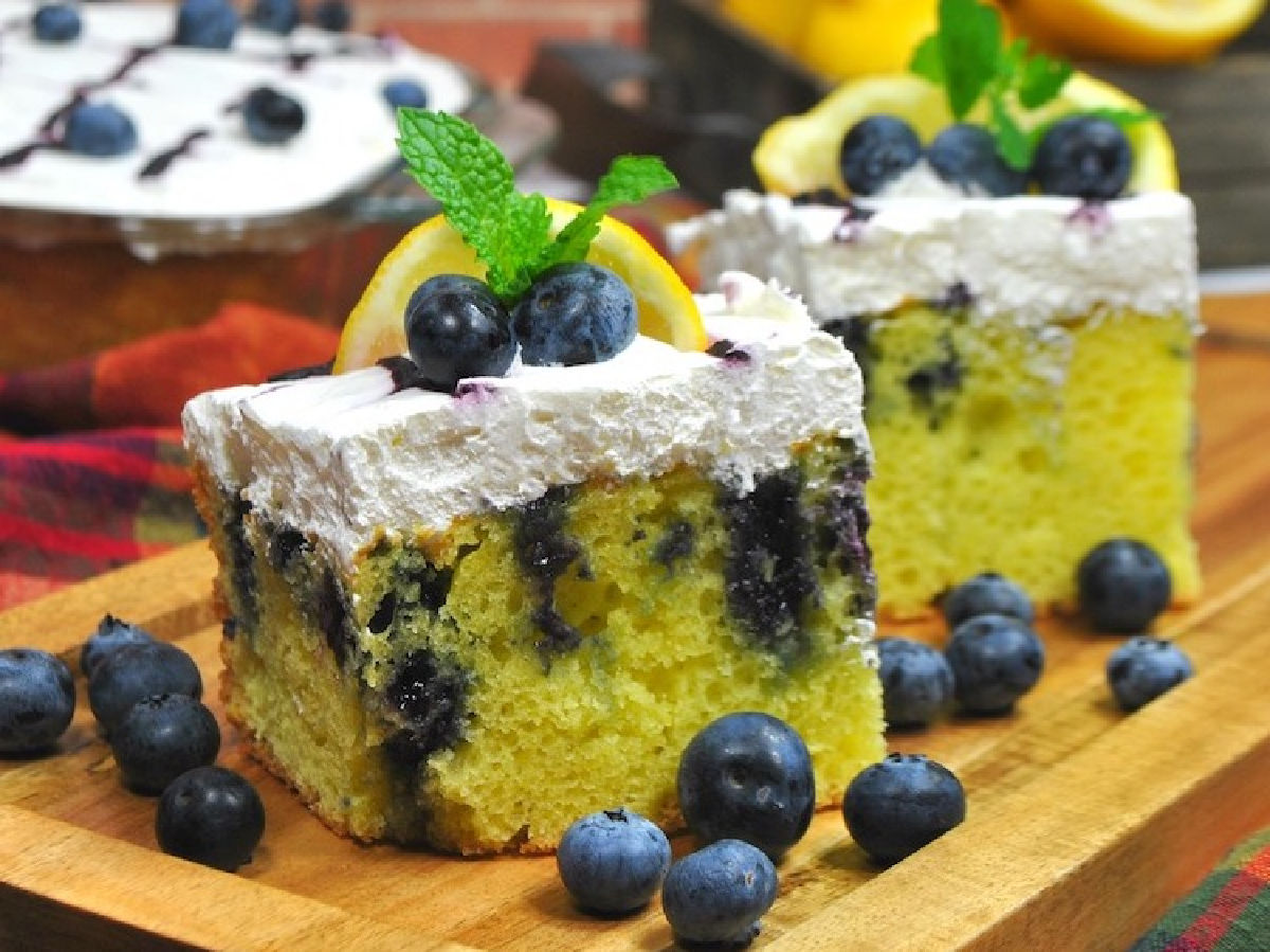 Lemon cake with blueberry jam poked inside with whipped cream topping.
