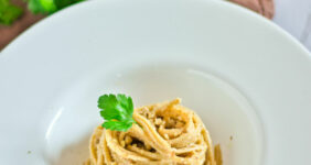Walnut sauce with pasta in a white dish for Pinterest.