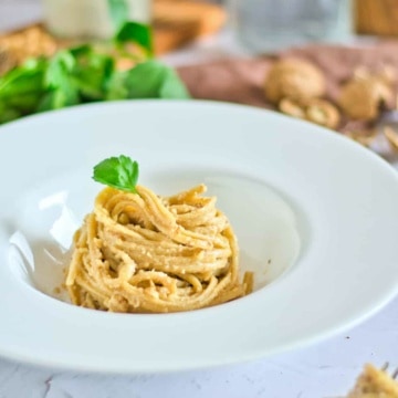 Walnut sauce with pasta topped with parsley in a white dish.