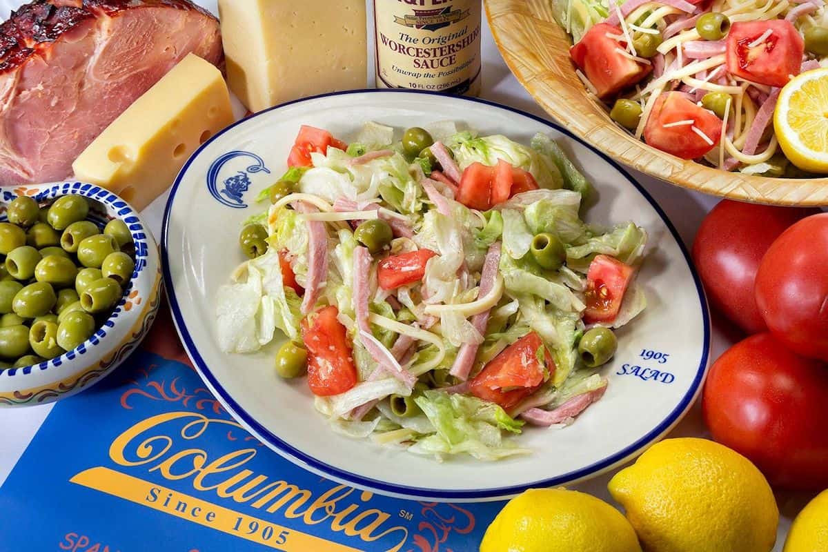 Salad on a white and blue plate with lemons on the side.