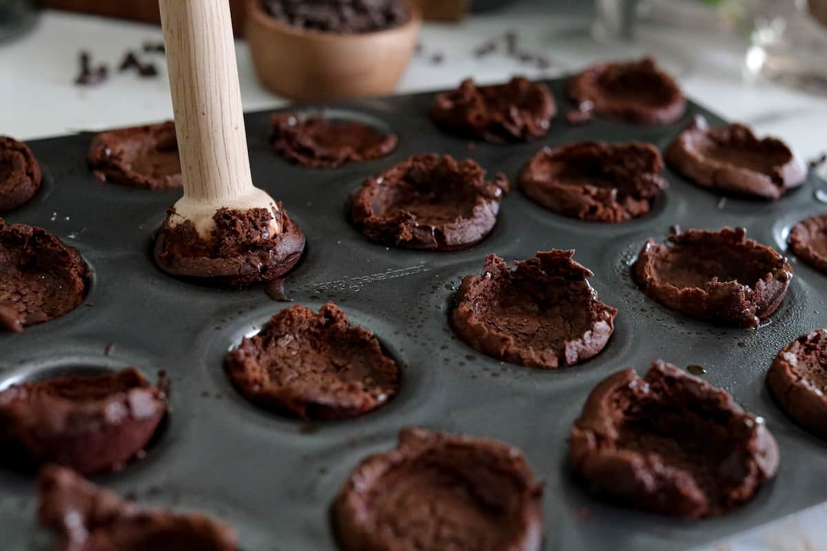 Brownie bites being smashed down for filling.