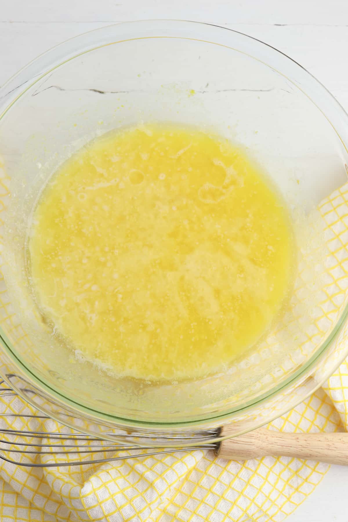 Butter, sugar, eggs, lemon extract, lemon zest, lemon juice, and milk in glass bowl.