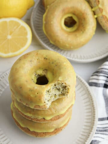 Lemon donuts stacked on a white plate with a black and white cloth.