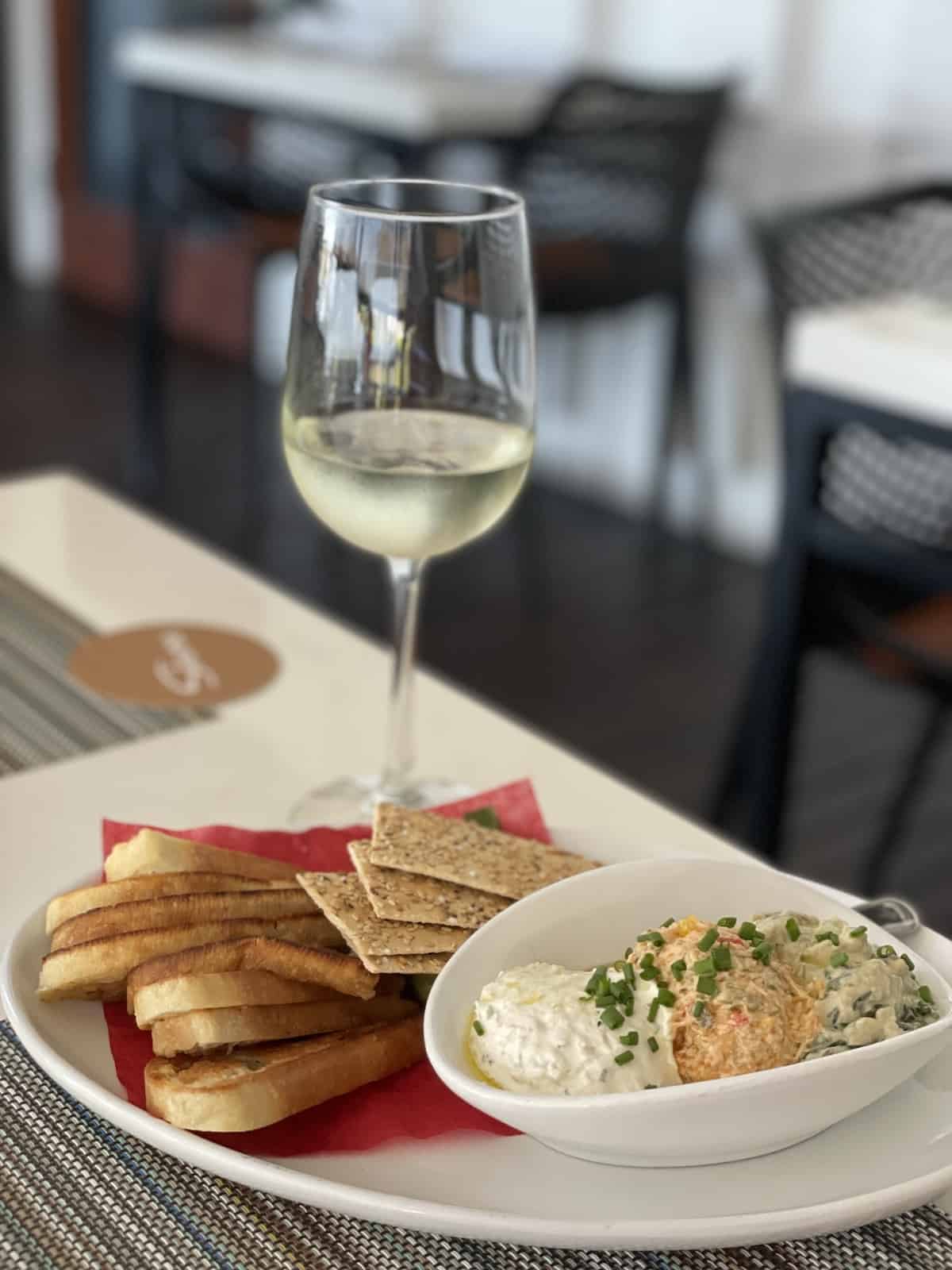 Glass of wine and fish dip with bread and crackers.