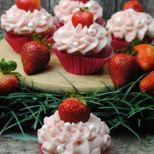 Cupcakes with pink icing and strawberry on top.