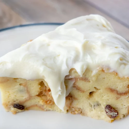 Bread pudding with cream cheese frosting on a white plate.