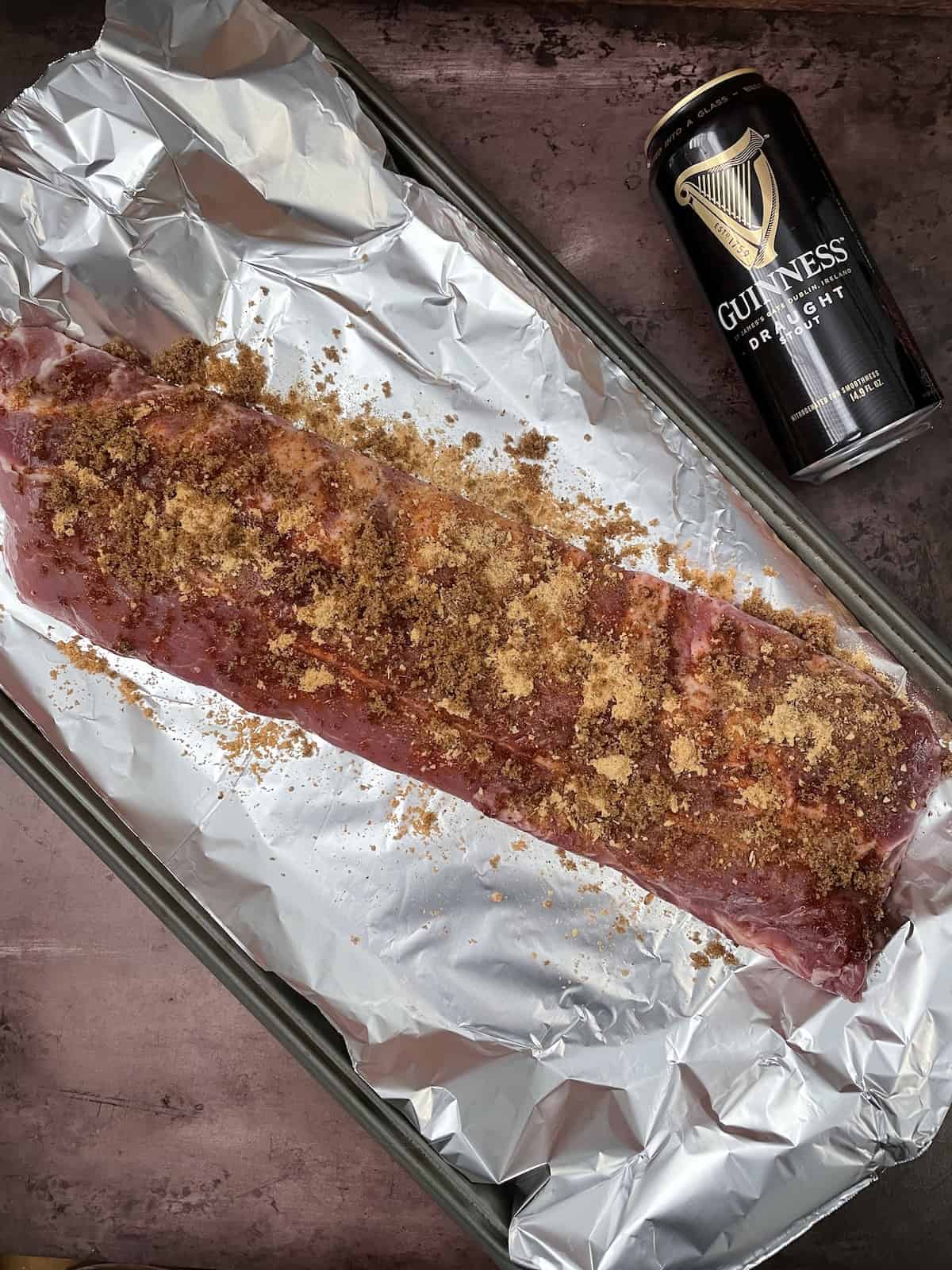Spare ribs with seasoning on foil on baking sheet.