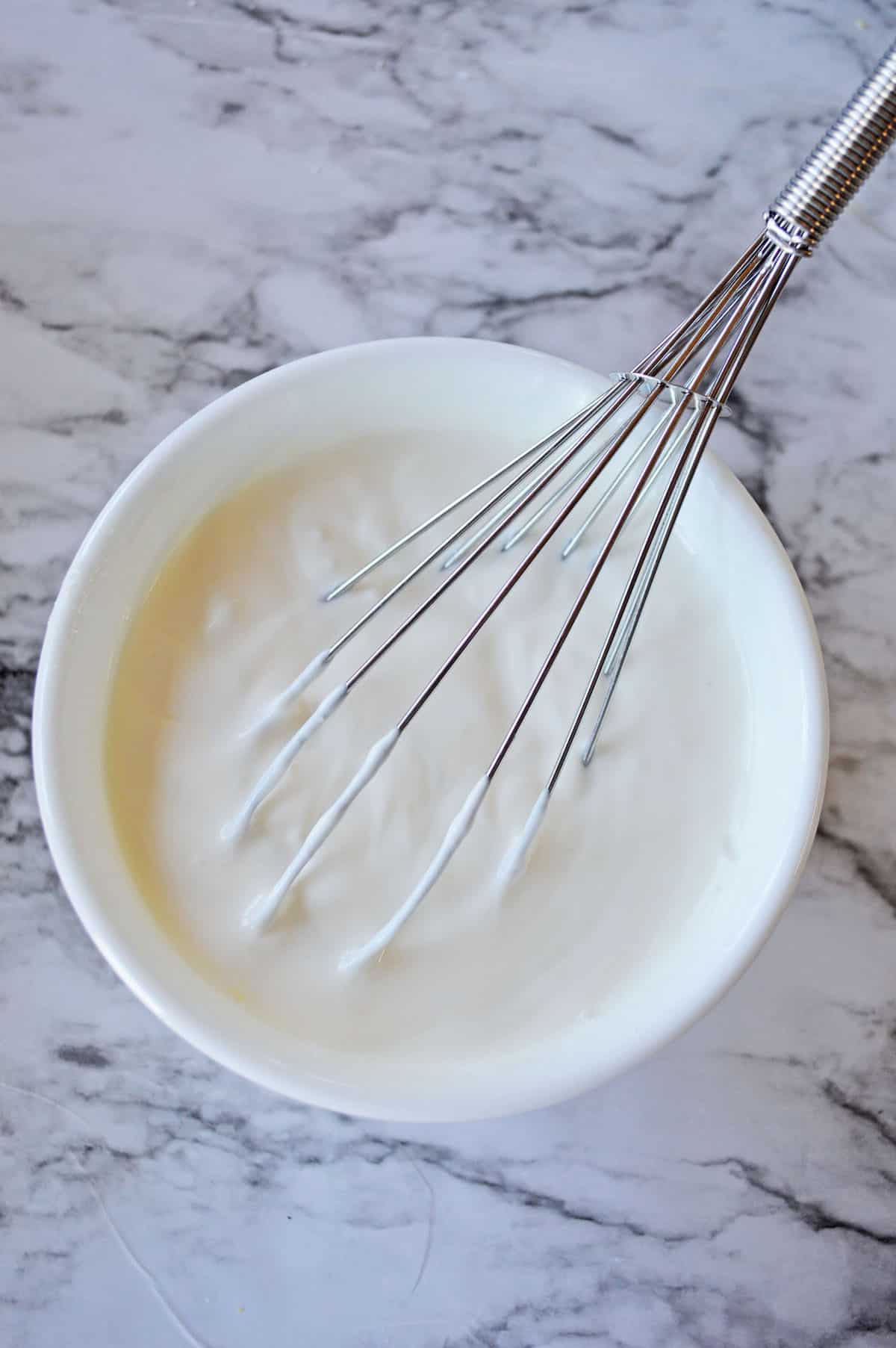 Sour cream and lemon in a white bowl with a whisk.