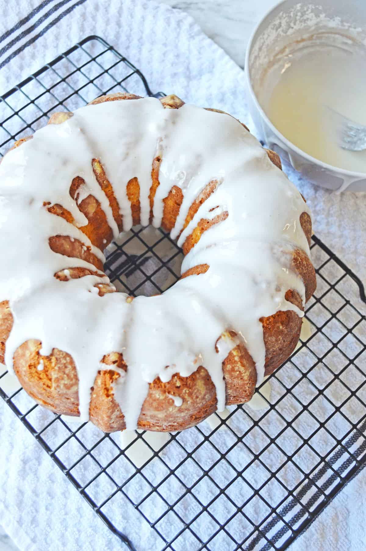 Whole Italian lemon pound cake with icing on a wire rack.