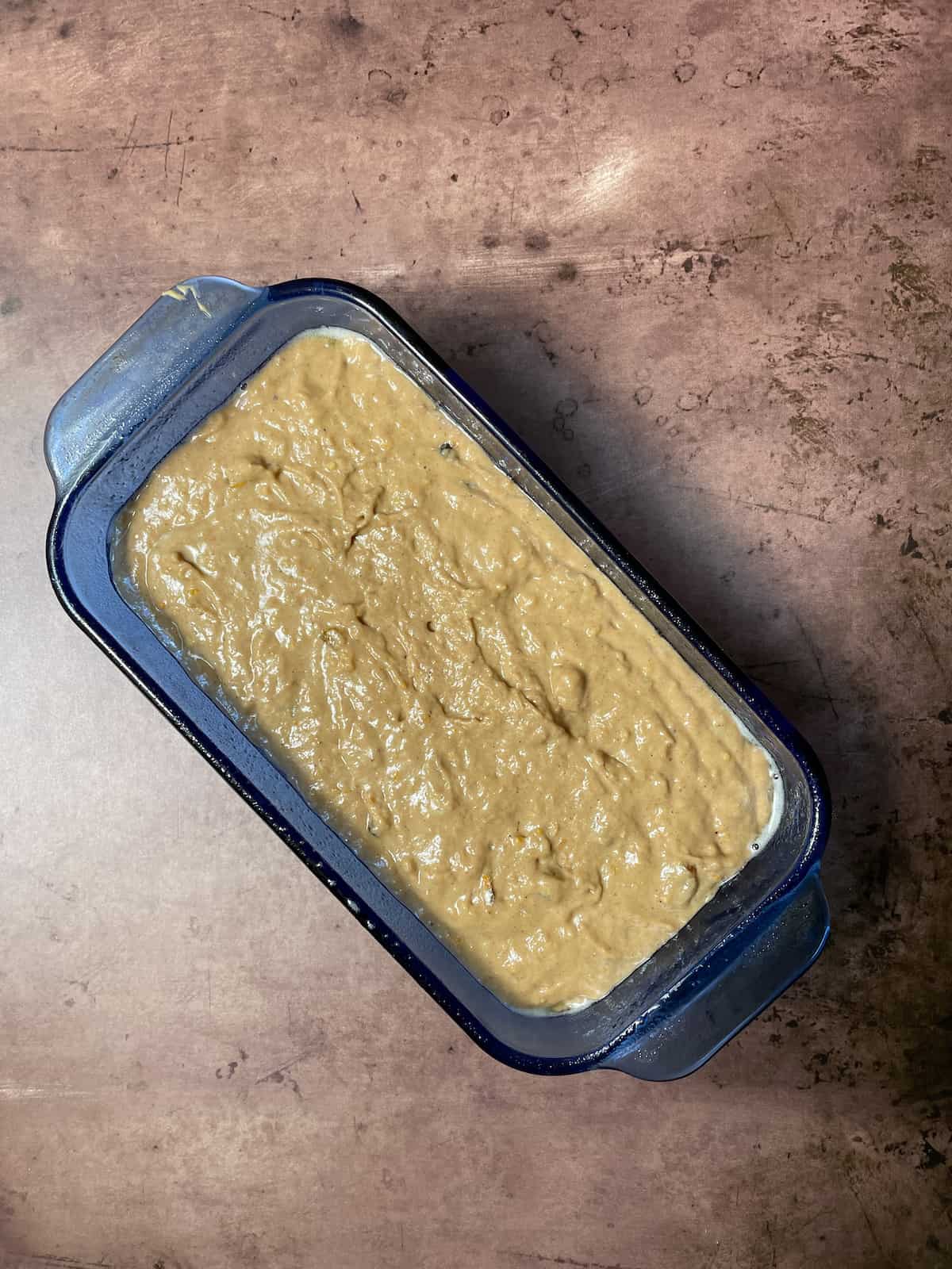 Spice bread batter in blue loaf pan on table.