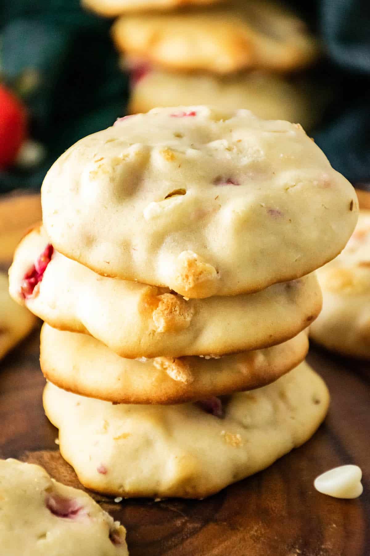 Strawberry cheesecake cookies stacked on a wood slab.