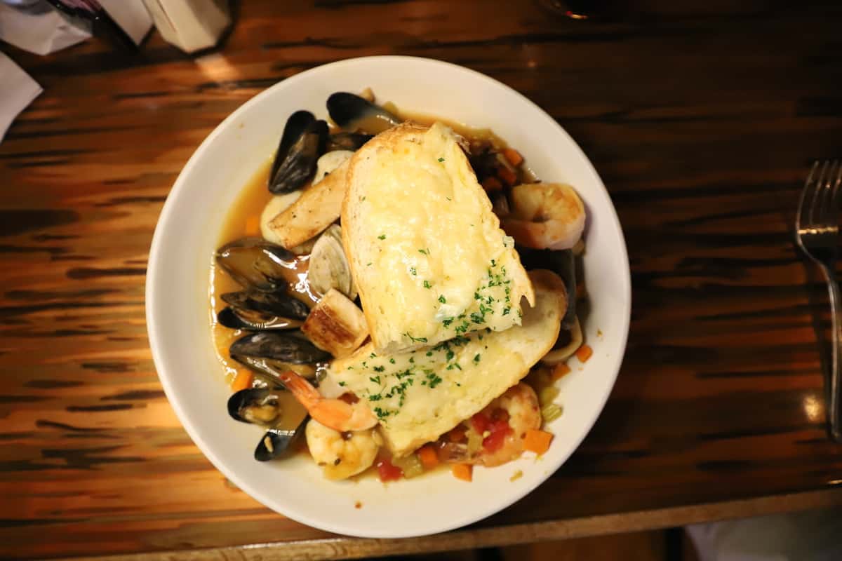 Mussels and shrimp with cheese garlic bread on a wood table.