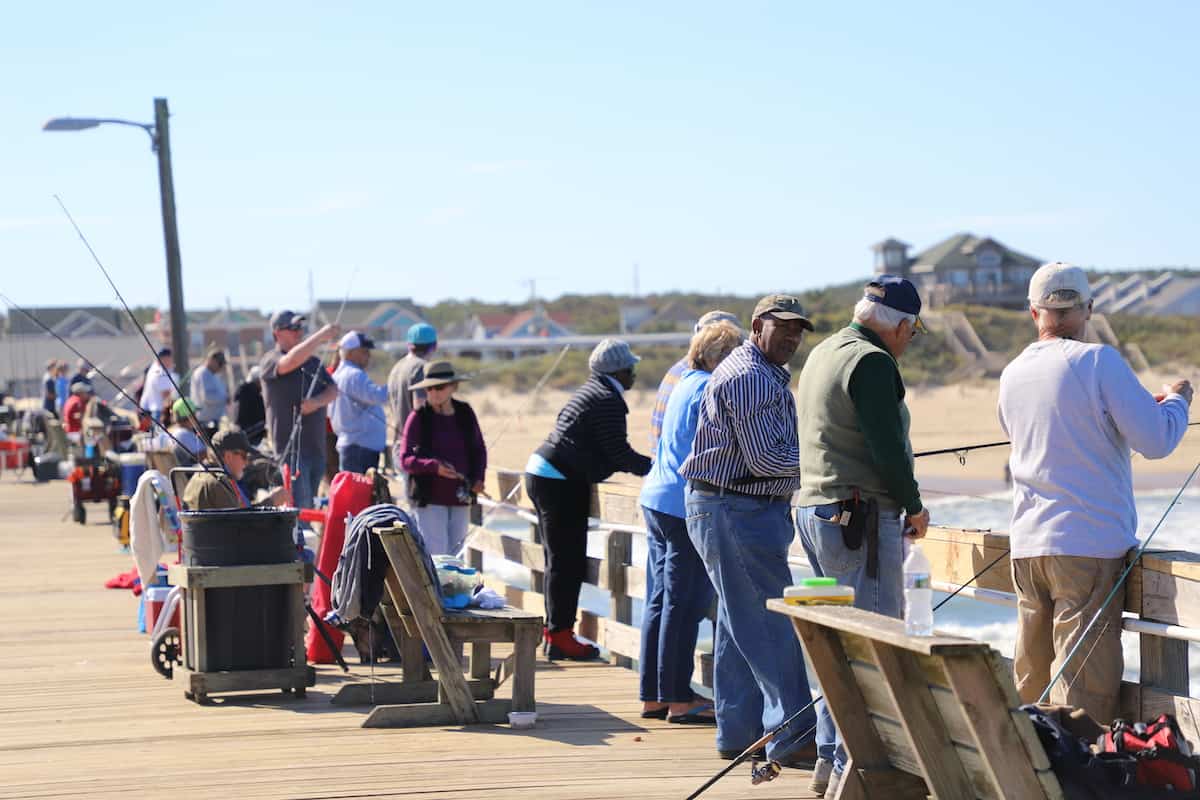 People fishing on a pier at the beach.