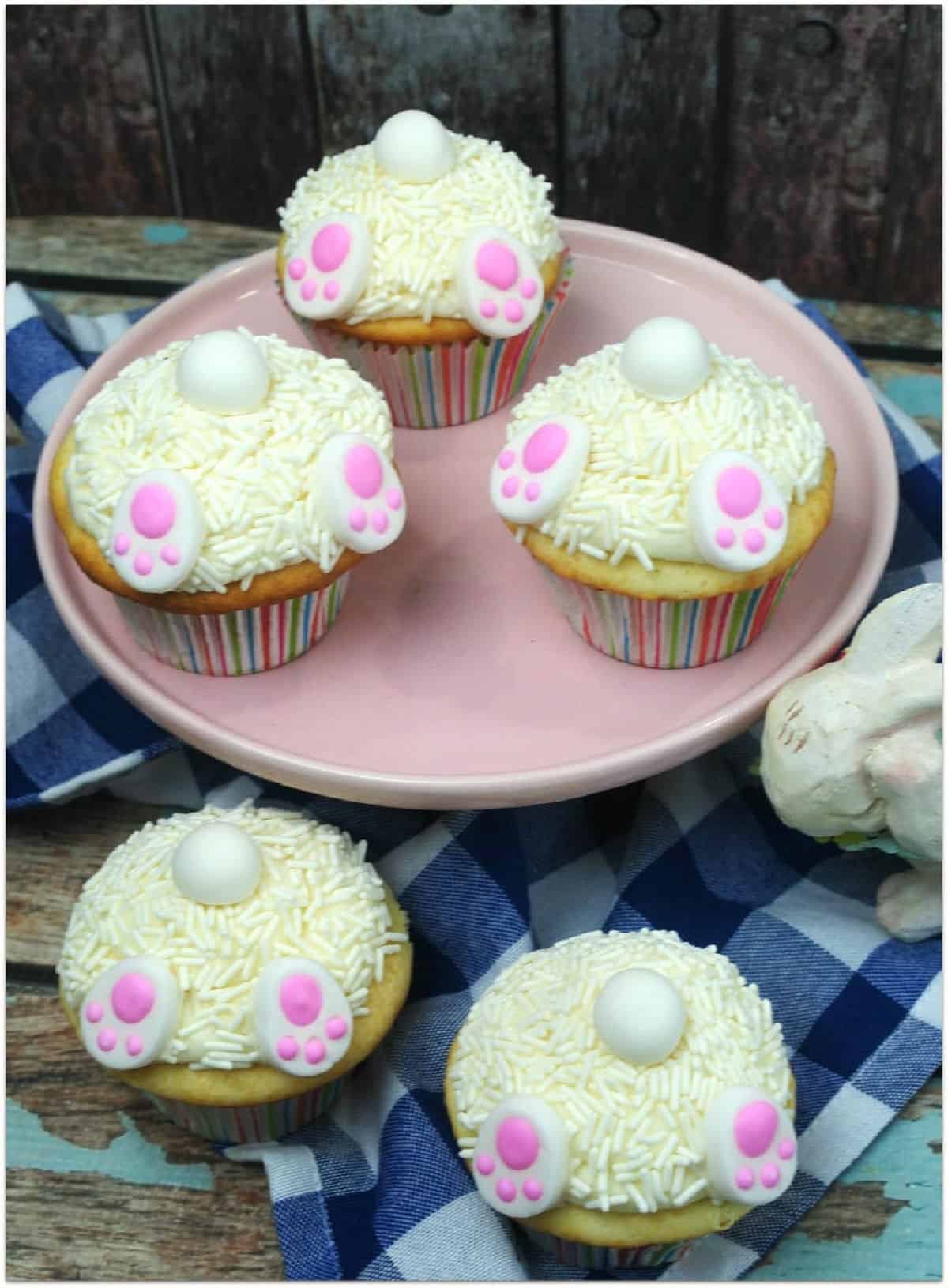 Bunny butt cupcakes on a blue wood board with blue and white checked cloth.