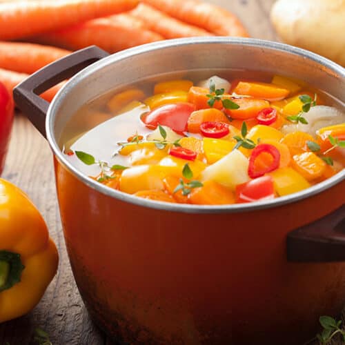 Garden vegetable soup in an orange pot.