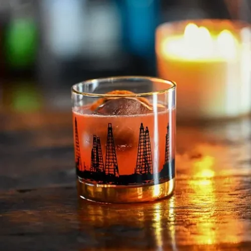 Whiskey cocktail in a glass with candle in background.
