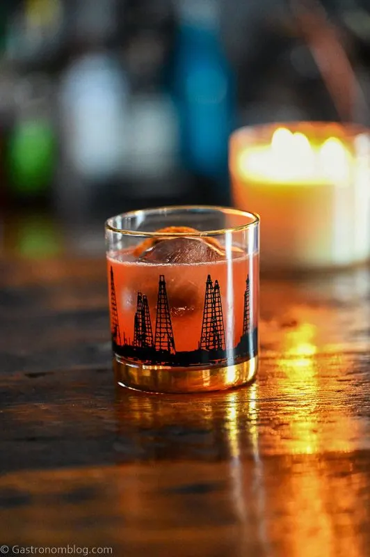Whiskey cocktail in a glass with candle in background.