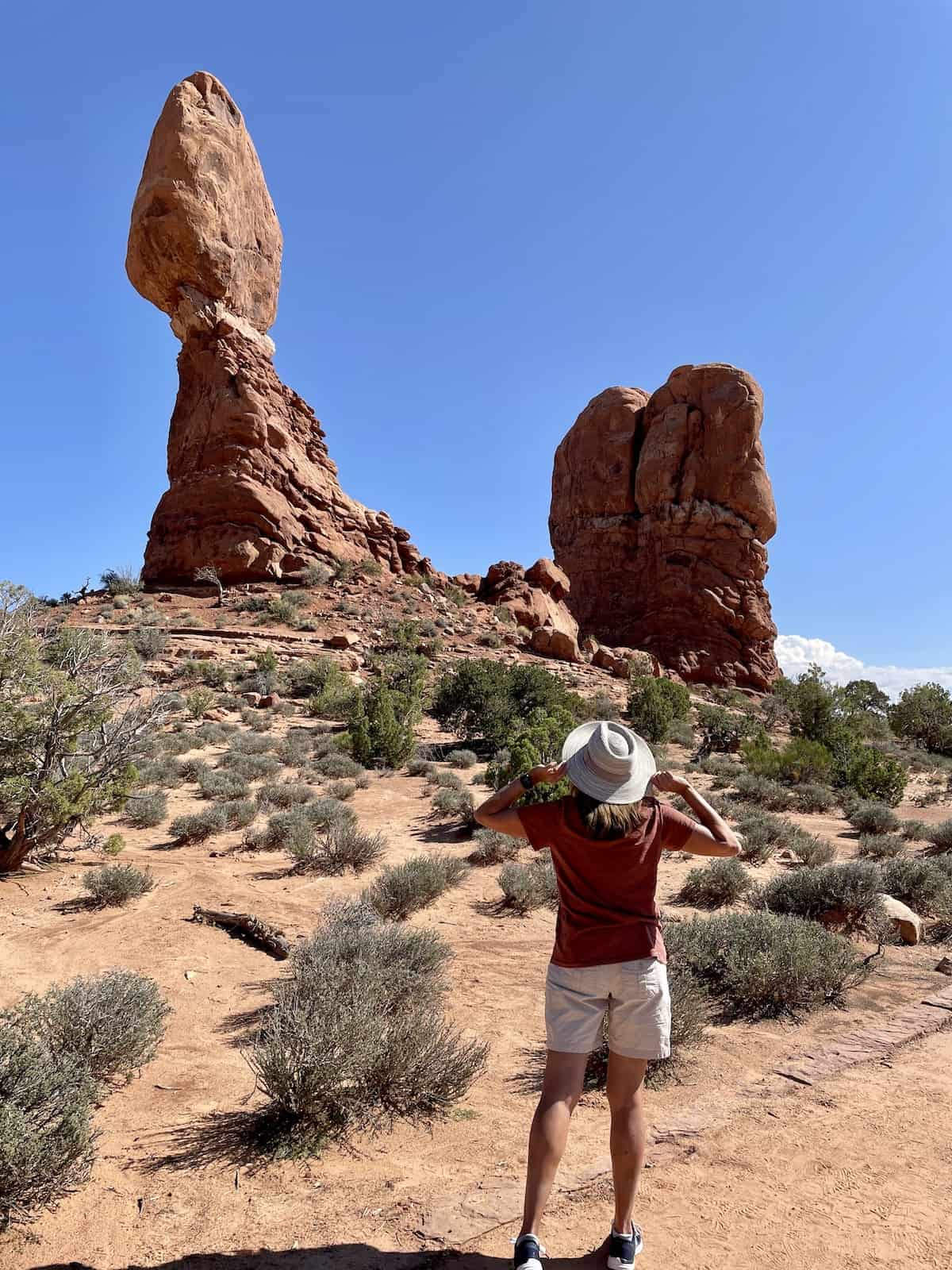 Woman in hat at Balanced Rock in Arches National Park.