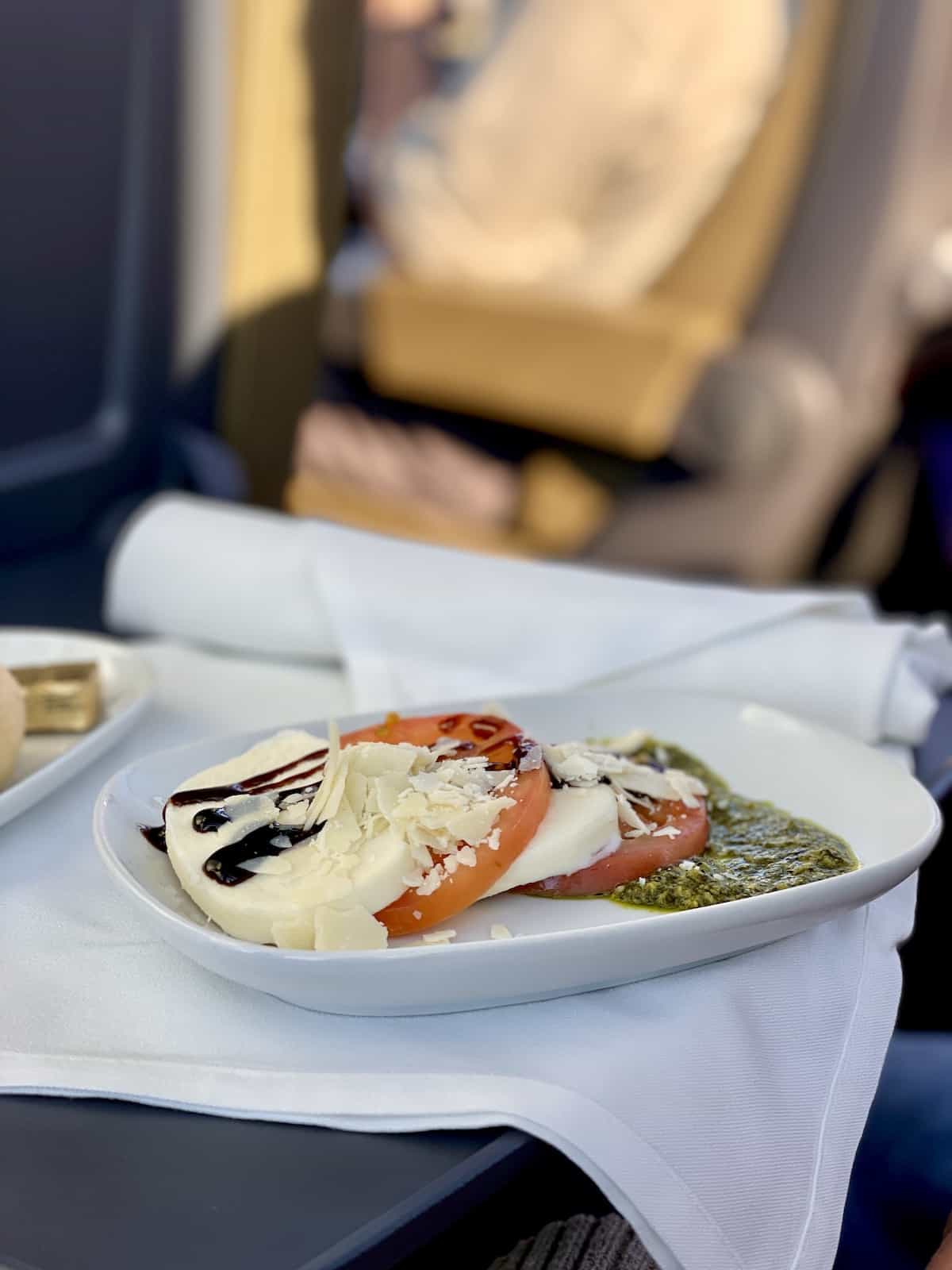 Caprese salad in a white plate on a white napkin.