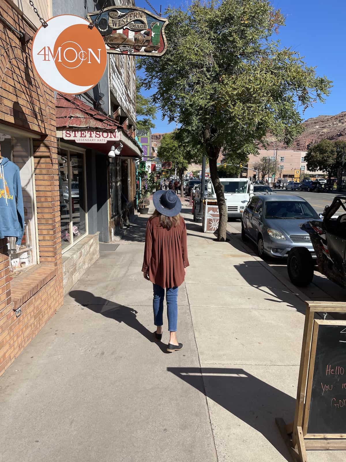 Woman in hat walking down street.