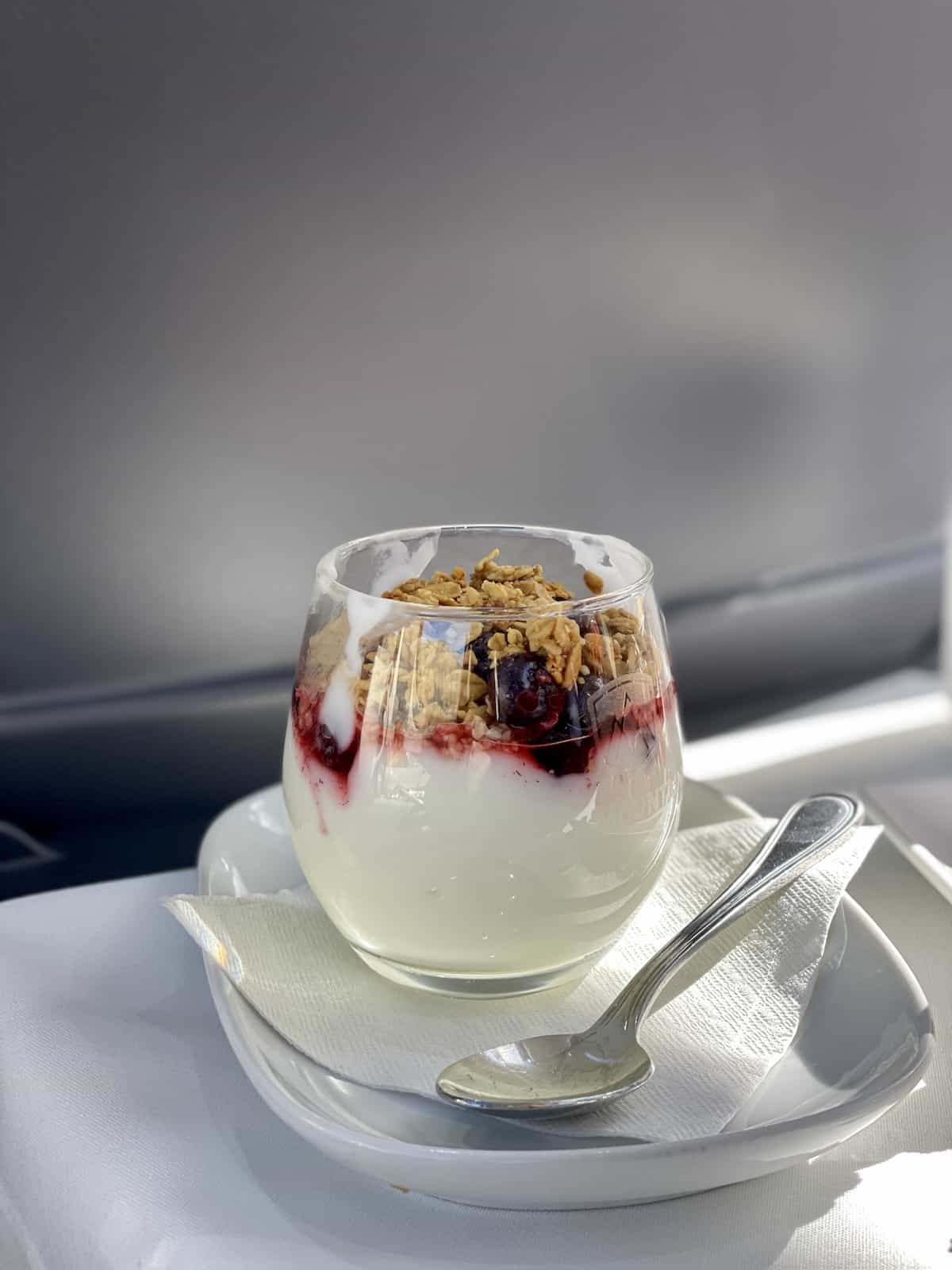 Parfait of yogurt and berries and granola in a glass on a white napkin with a spoon.