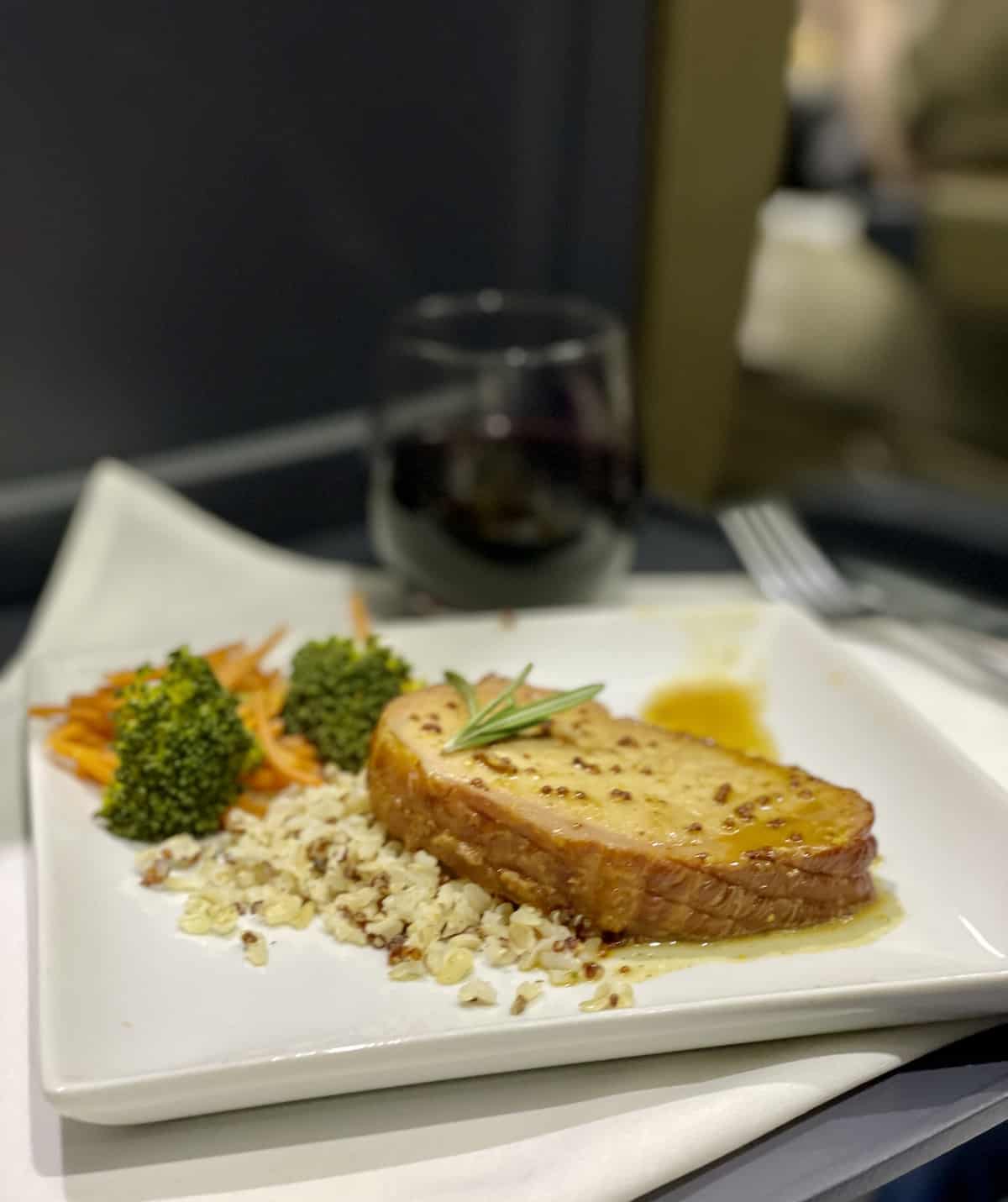 Pork tenderloin with rive and vegetables on a white plate on a white napkin.