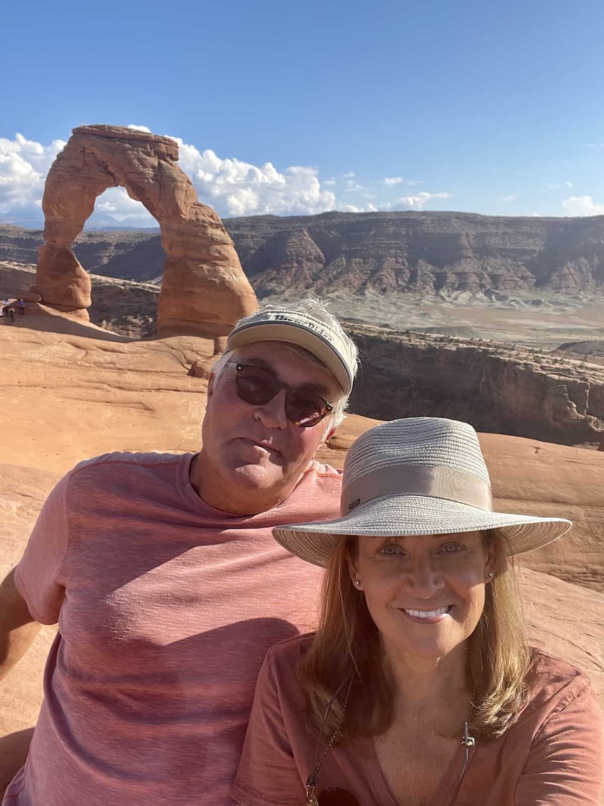 Delicate Arch behind couple in Arches National Park.