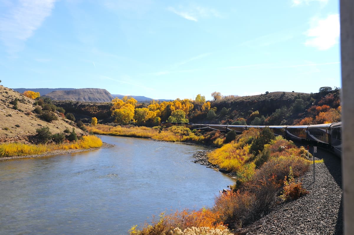 Train running along river in fall.