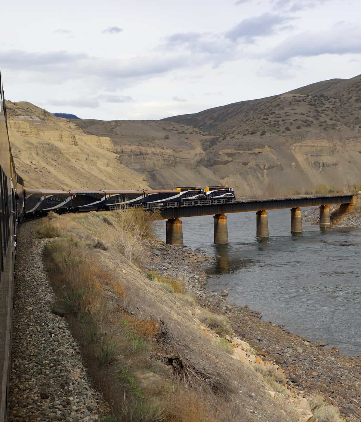 Rocky Mountaineer train going across bridge over water.