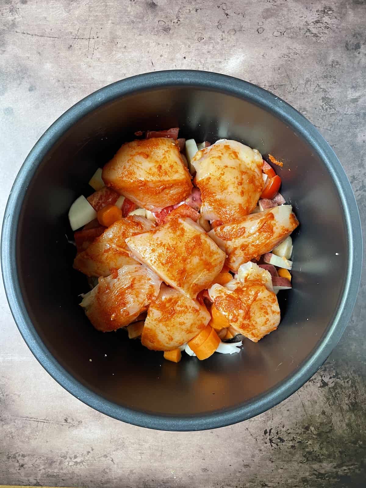 Chicken on top of veggies in slow cooker.