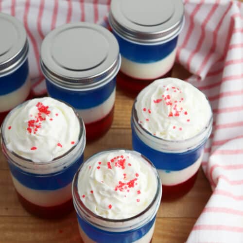 Mason Jars with jello parfait and whipped cream on top.
