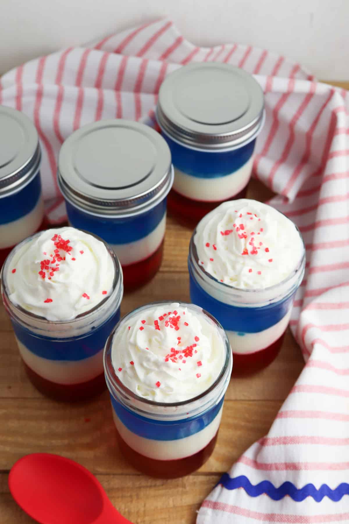 Mason Jars with jello parfait and whipped cream on top.