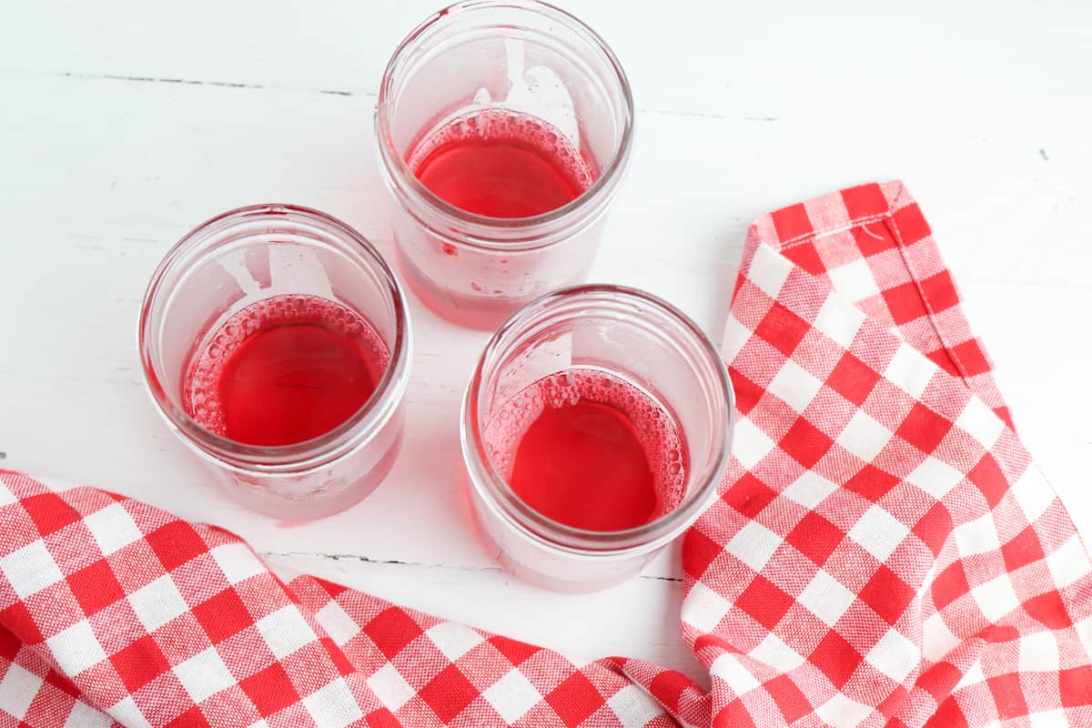 Red jello mixture in bottom of mason jar.