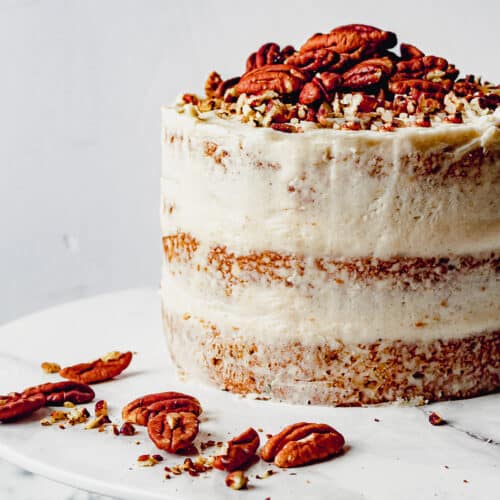 Butter pecan cake on a white platter with pecans.