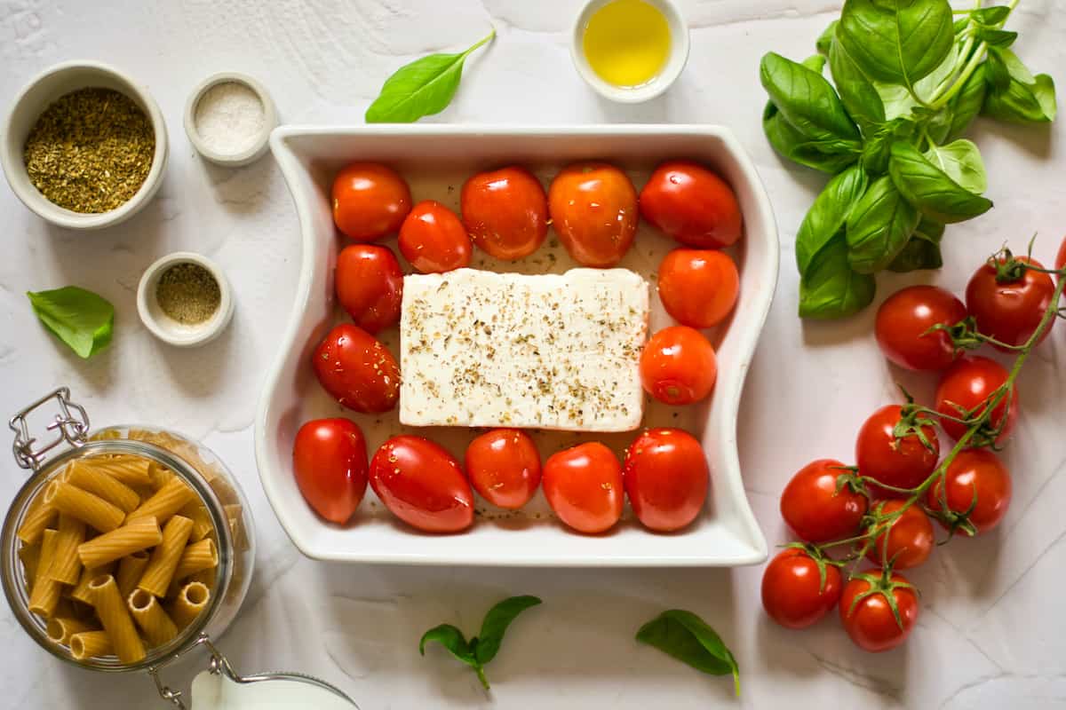 Feta topped with spices and tomatoes in white dish.